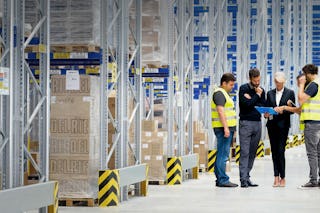 Fünf Personen im Gespräch vor einem Palettenregal