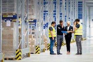 Fünf Personen im Gespräch vor einem Palettenregal