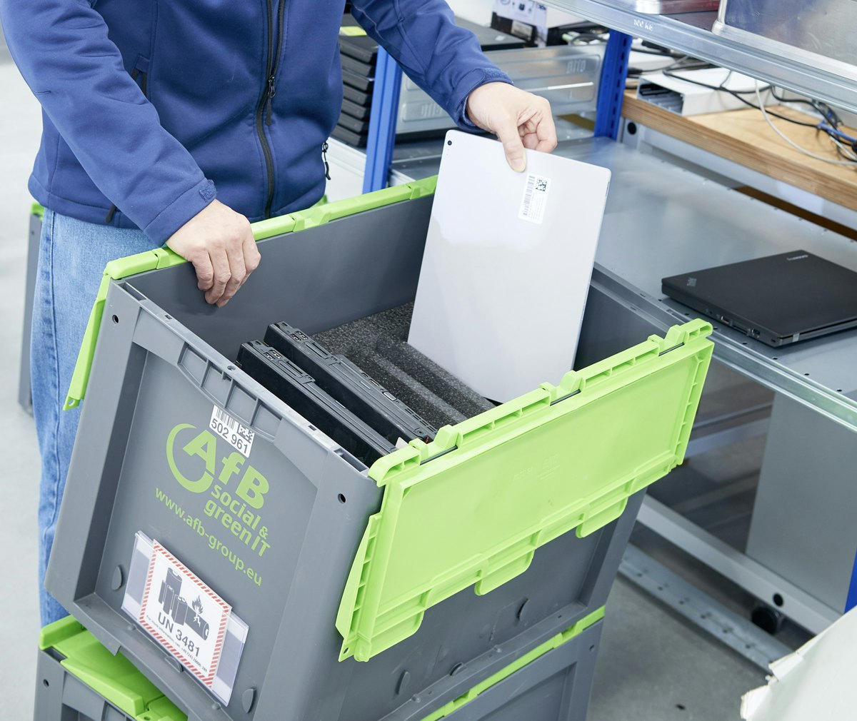 Mitarbeiter packt Laptops in Behälter die mit speziellem Inlay ausgestattet sind.