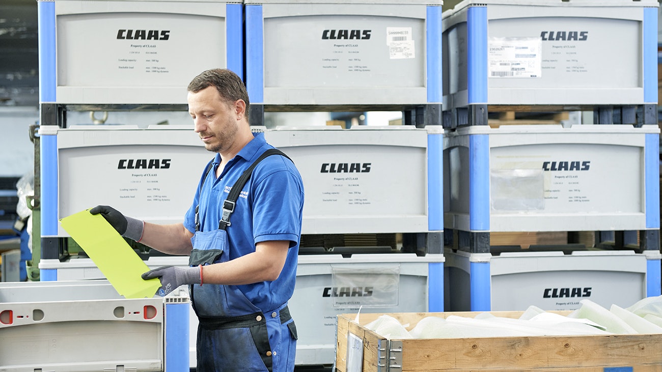 Ein Arbeiter legt Ware in Schwerlastbehälter SL mit Kufen