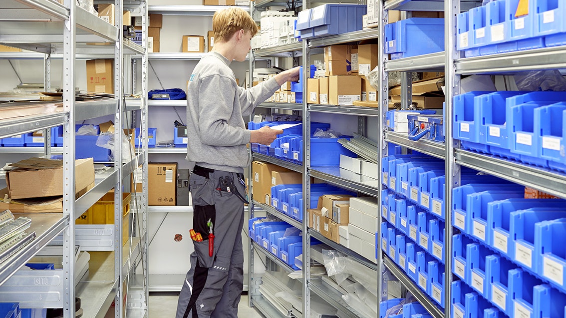 Ein Arbeiter entnimmt Ware aus einem Kleinteilelager