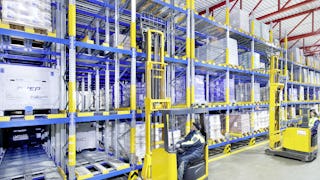 Twee medewerkers op interne transportvoertuigen die pallets uit een doorloopstelling halen.