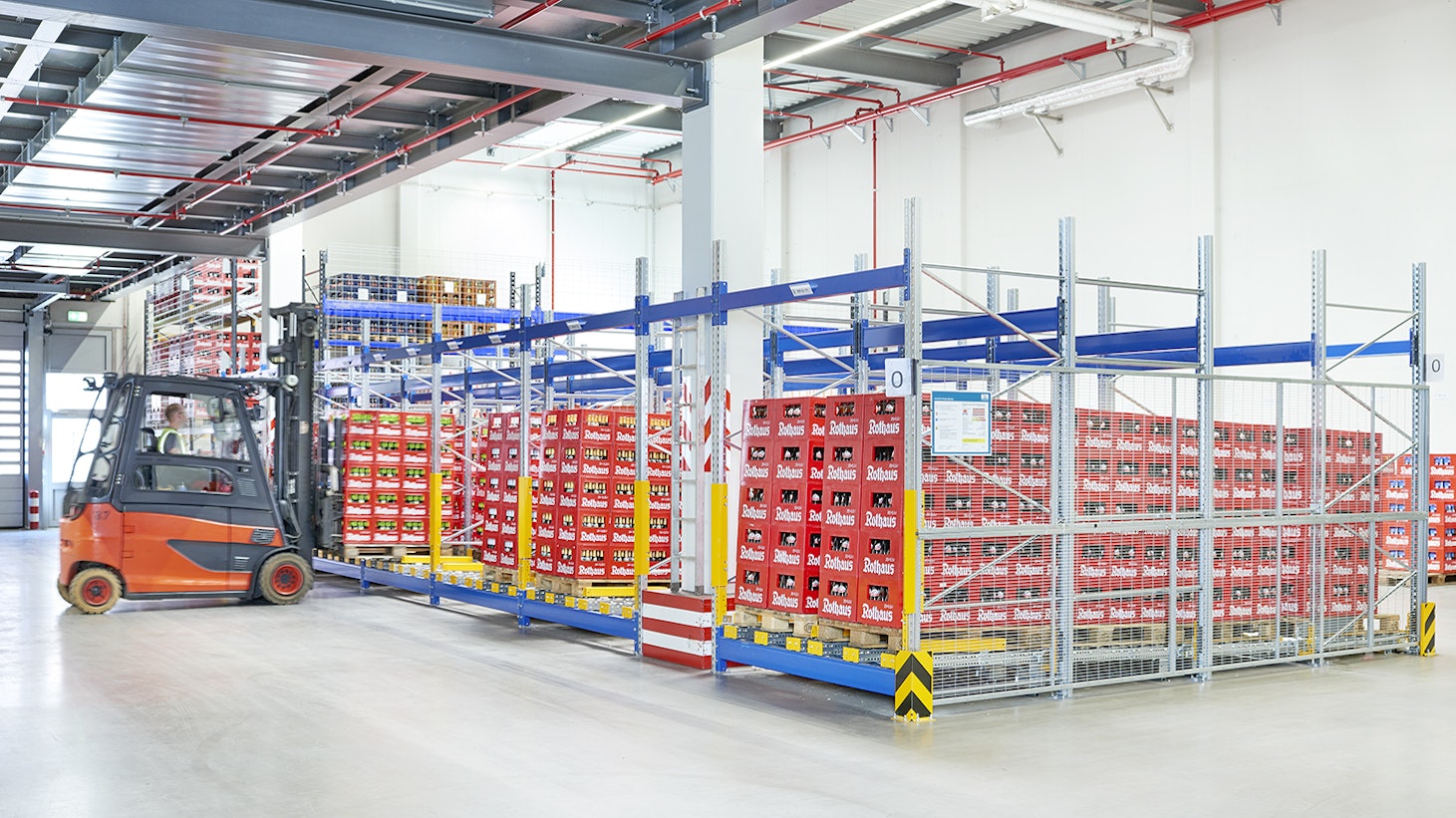 Ein Mitarbeiter auf einem Flurförderzeug er eine Palette in ein Palettendurchlaufregal stellt.