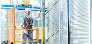 Ein Mitarbeiter steht in einem Personenkorb und befestigt den easyHook um sich zu Sichern