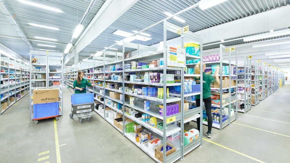 Zwei Frauen räumen ein Fachbodenregal ein