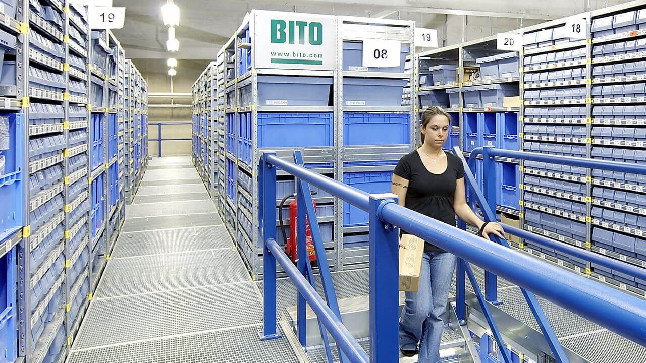 Mitarbeiterin geht die Treppe einer Lagerbühne hinunter