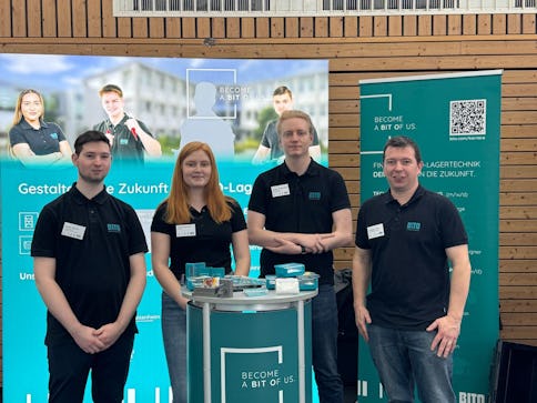 Vier BITO Mitarbeiter und Mitarbeiterinnen vor BITO Werbebannern