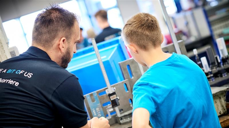 Ein BITO Mitarbeiter erklärt einem Jugendlichen die Arbeit in der Metallwerkstatt