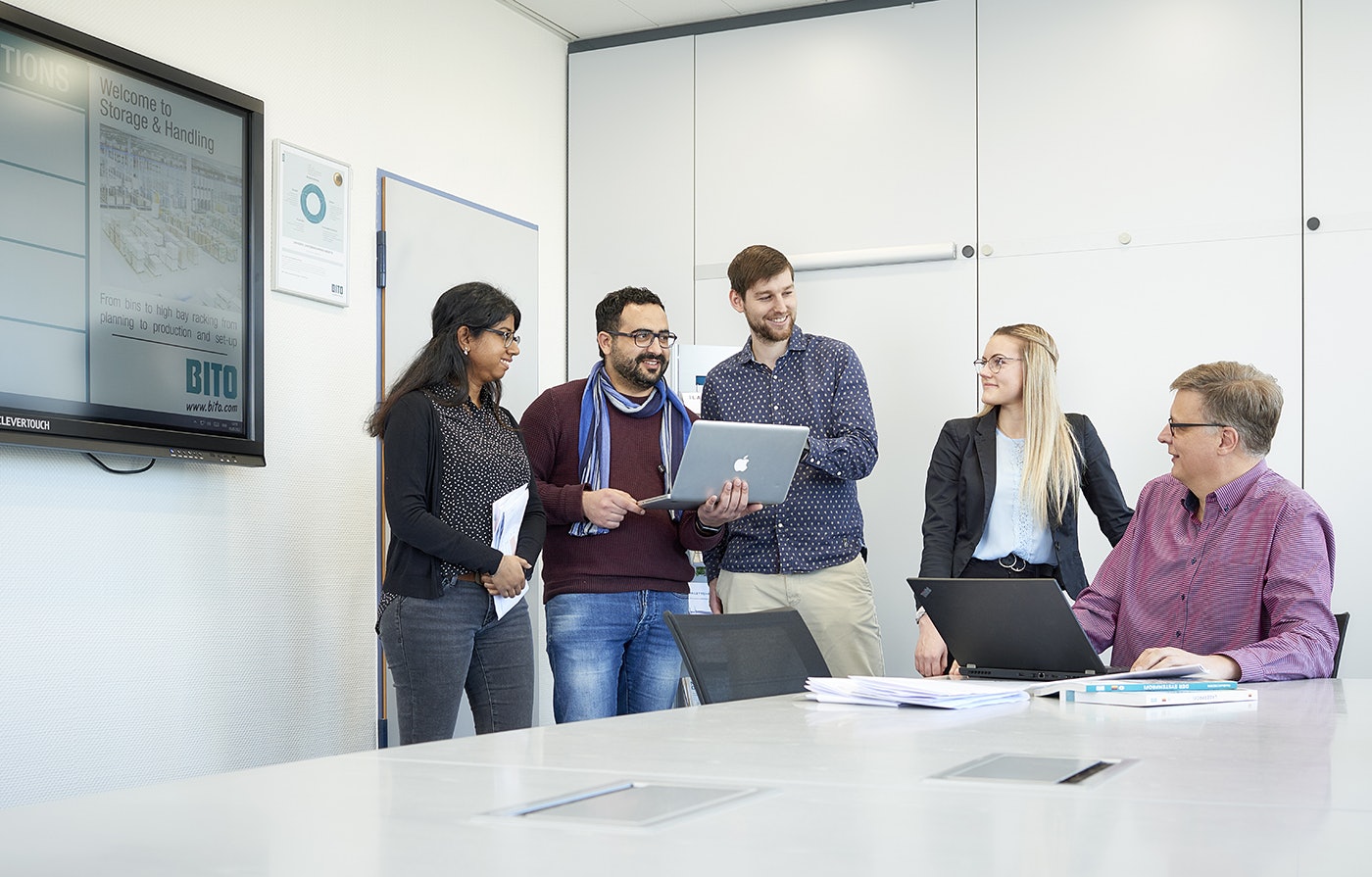 Eine Gruppe von Leuten, mit Laptops, im Gespräch.