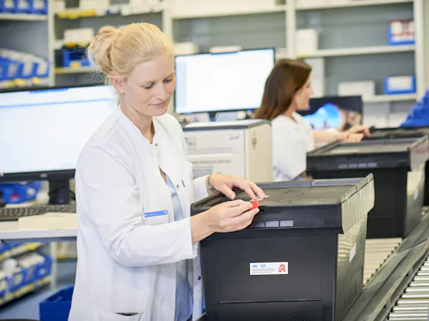 Frau in Laborkleidung mit Behälter