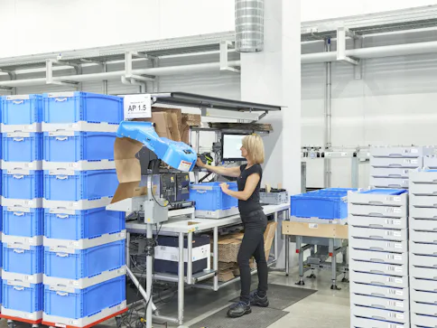 Frau arbeitet mit blauen Transportbehältern